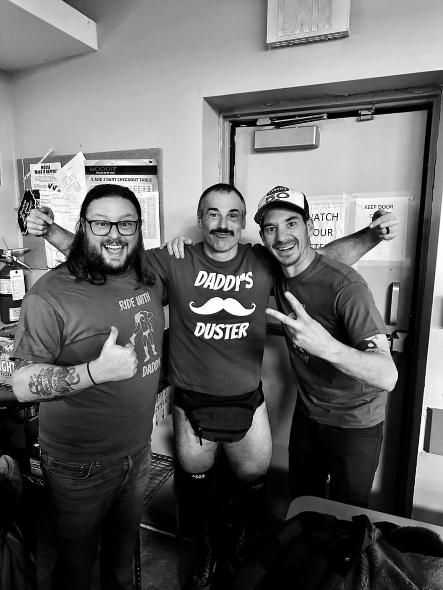 Three friends posing in a dart league room